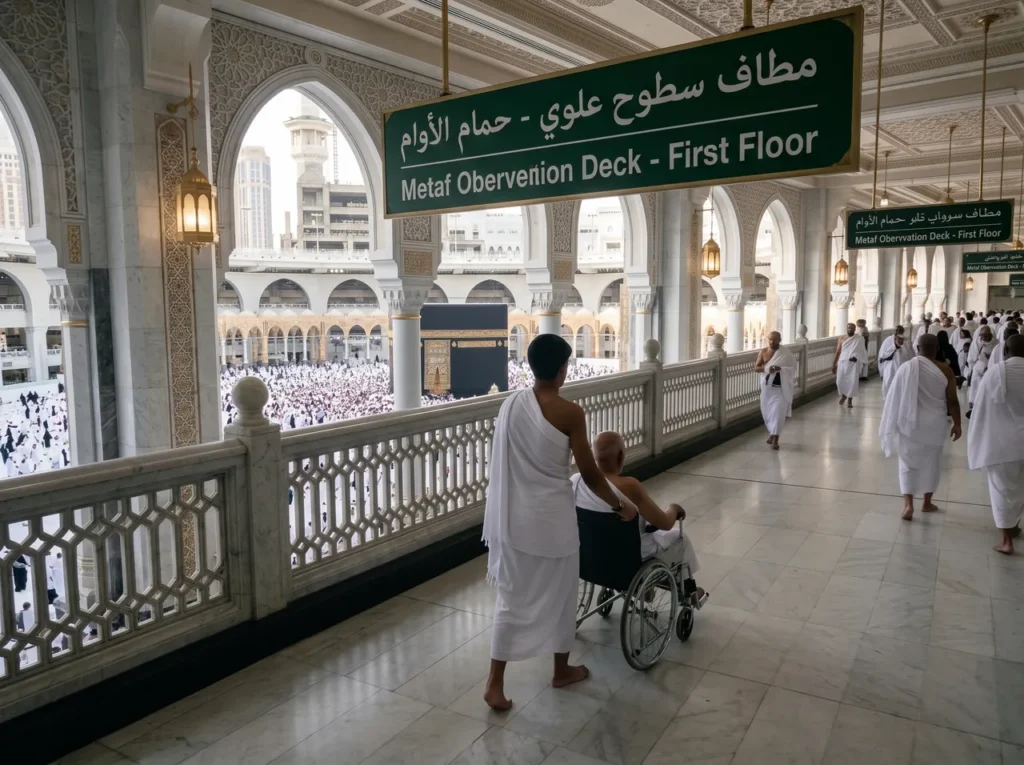 حاج مسن على كرسي متحرك يدفعه قريبه في ممر الطواف المطل على الكعبة